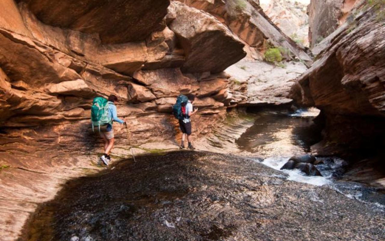 Grand Staircase-Escalante | Photo Gallery | 1 - Grand Staircase-Escalante National Monument Two hikers walking down river in slot canyon by Grand Staircase