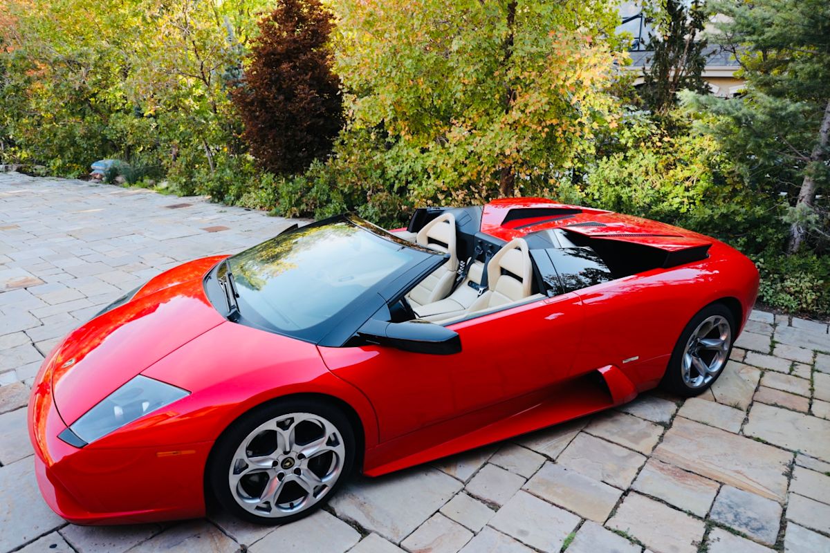 A red Lamborghini sits on a pavement. 