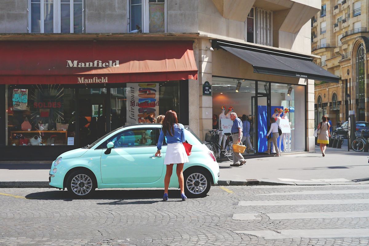 a woman standing near a green car