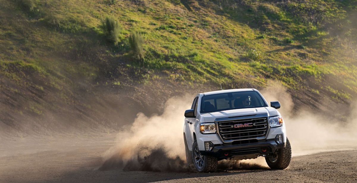 A white 2022 GMC Canyon driving in the dust