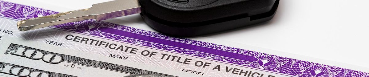 A key rests on a car title and hundred dollar bills