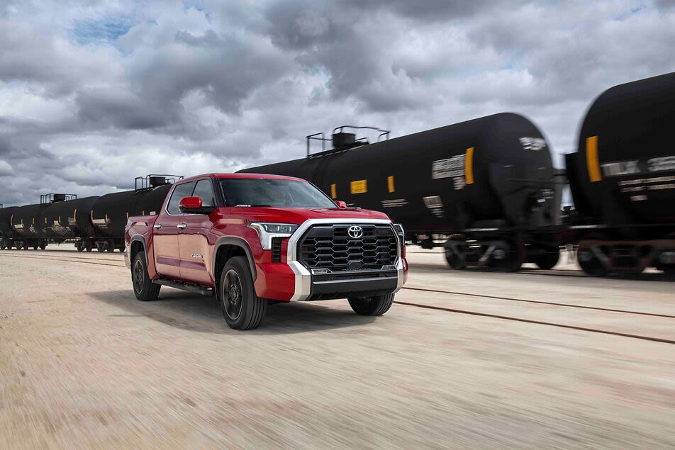 a red Toyota Tundra near a train
