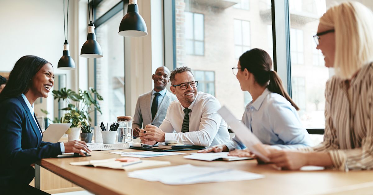Coworkers display emotional intelligence in the workplace as they happily collaborate around a table