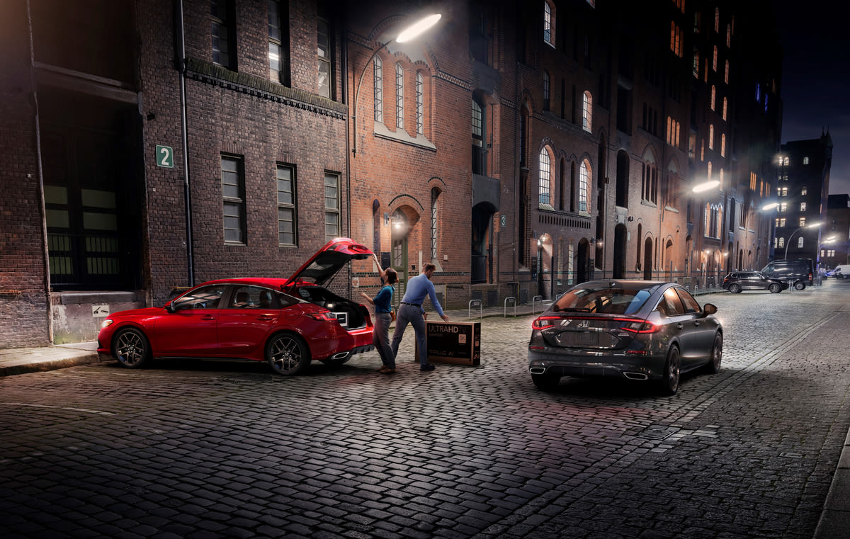 a red 2022 Honda Civic Hatchback near two people