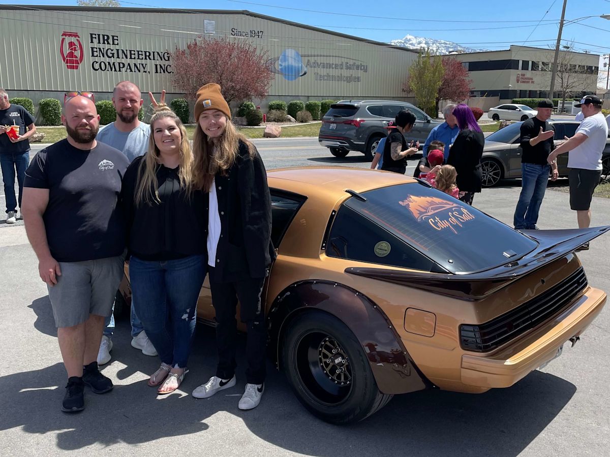 Nick Long, Gary Ashley, Kat Wall, and Jaden Wall stand in front of the renovated Mazda RX-7