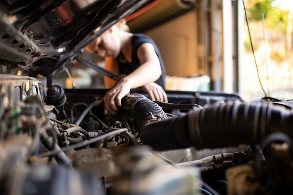 girl fixing under the hood of car