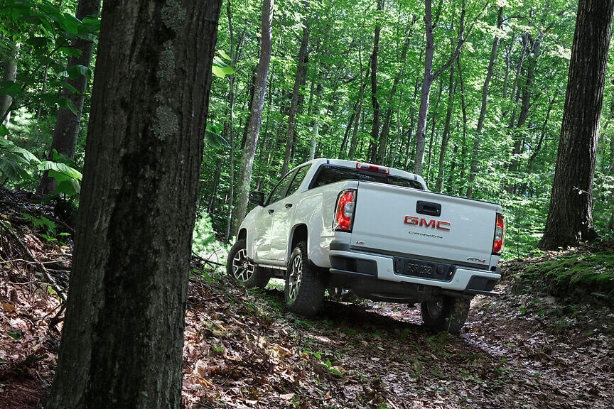 A white 2022 GMC Canyon AT4 in a forest.