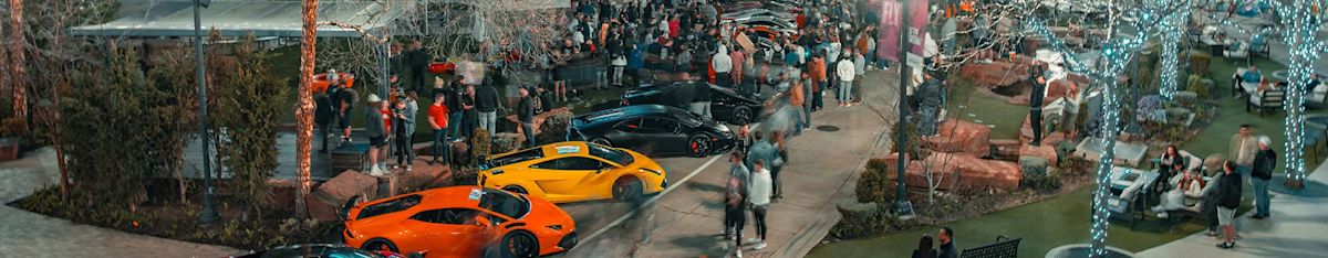 A crowd of people walks by a series of expensive cars at the Exotics at the Gateway Event. 