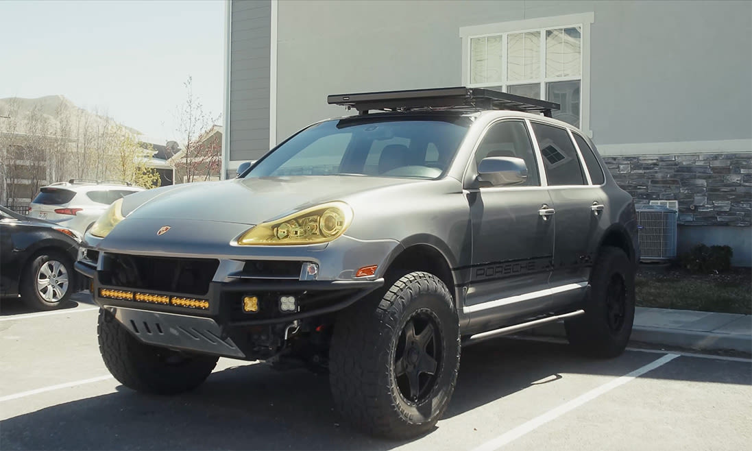 A grey Porsche Cayenne with large off-road tires.