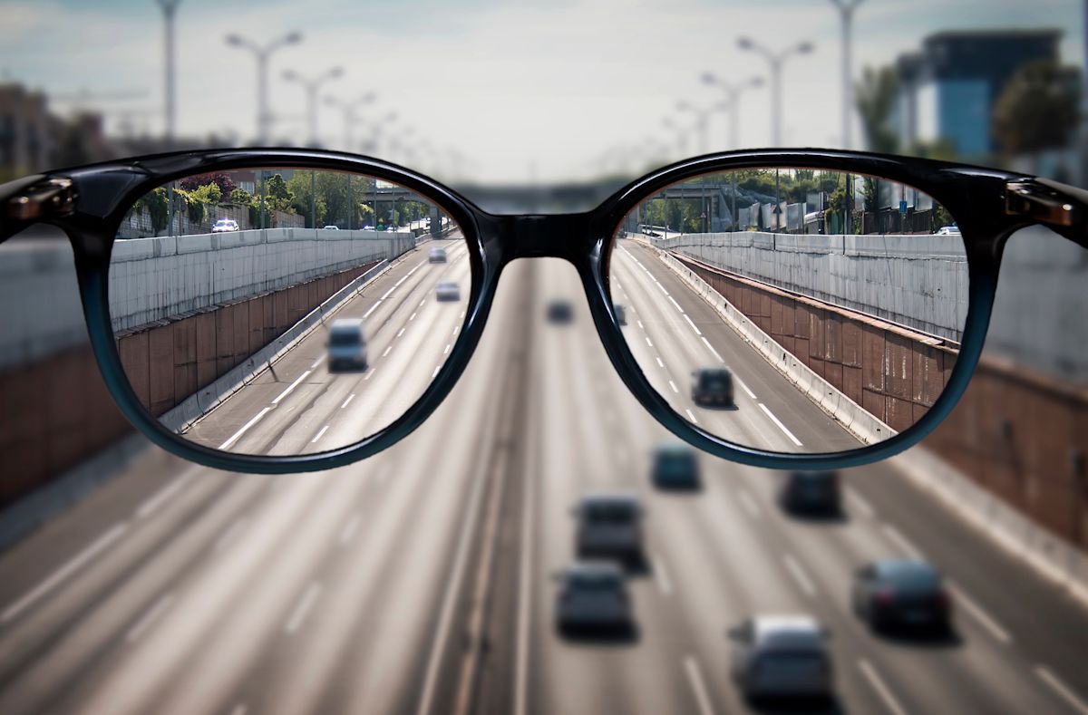 A busy freeway is seen in focus through a pair of glasses