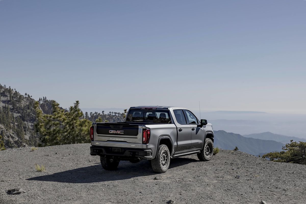 A silver GMC Sierra 1500 looks over a viewpoint with hazy mountains below. 