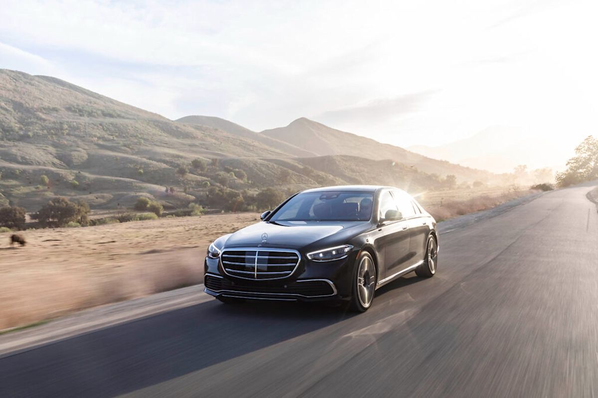 a black Mercedes-Benz S-Class driving up a road