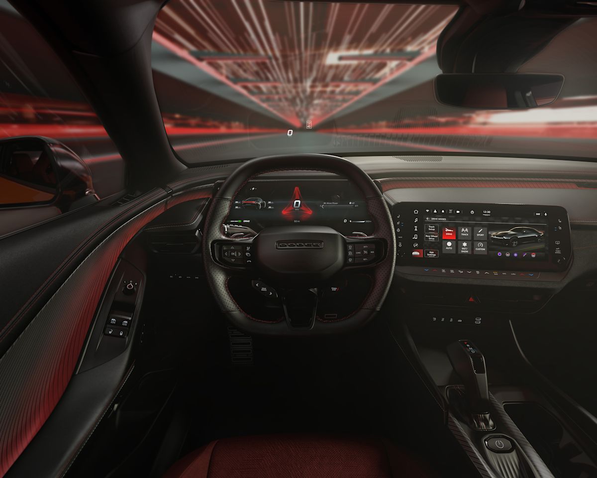 Red accents in the black interior of a Dodge Charger, with a view of the flat-top steering wheel and instrument panel