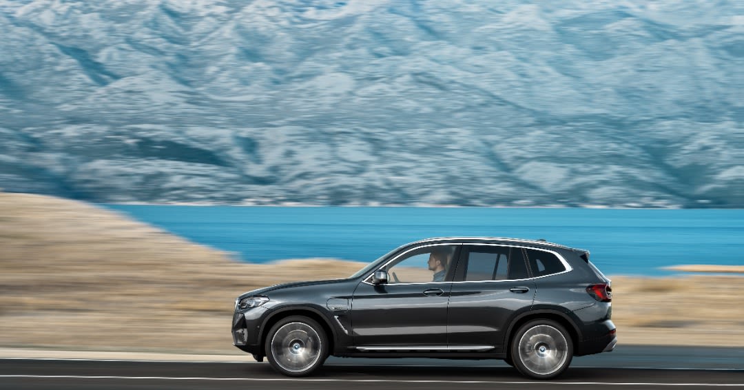 a man driving a black BMW X3 near water. 