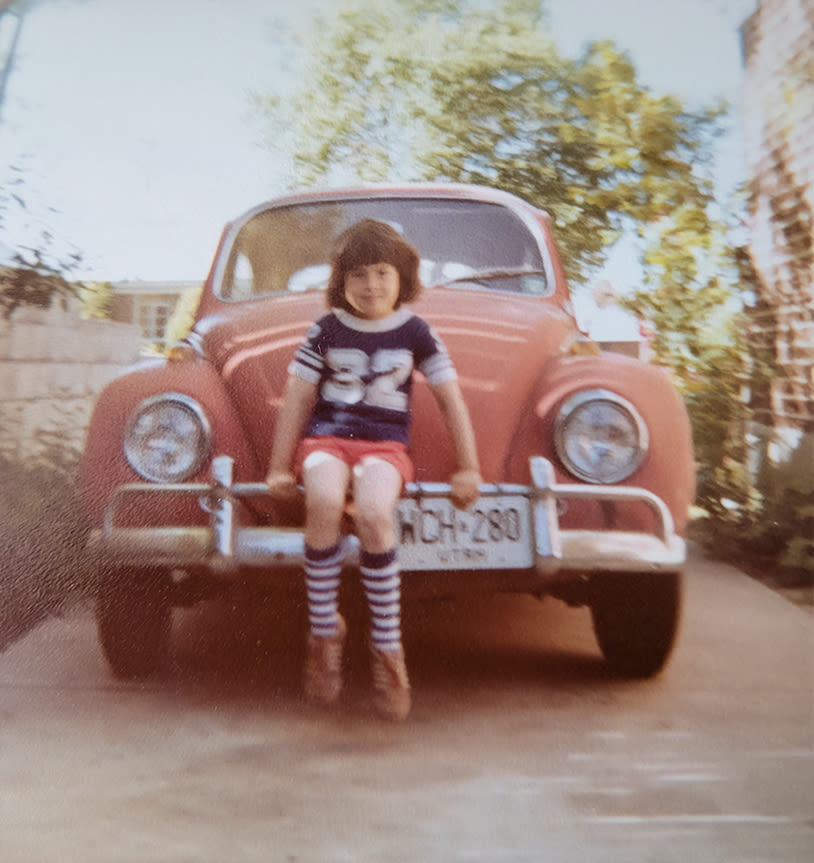 An old photo from the 1970s shows Johnny sitting on the chrome bumper of an earthy red VW Beetle
