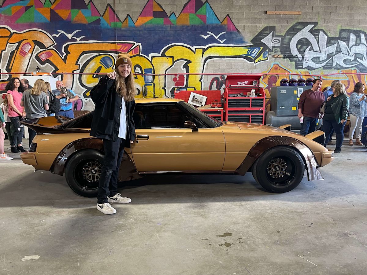 Jaden Wall stands in front of his Mazda RX-7 with keys in hand