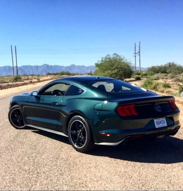 A Ford Mustang sits on a pavement. 