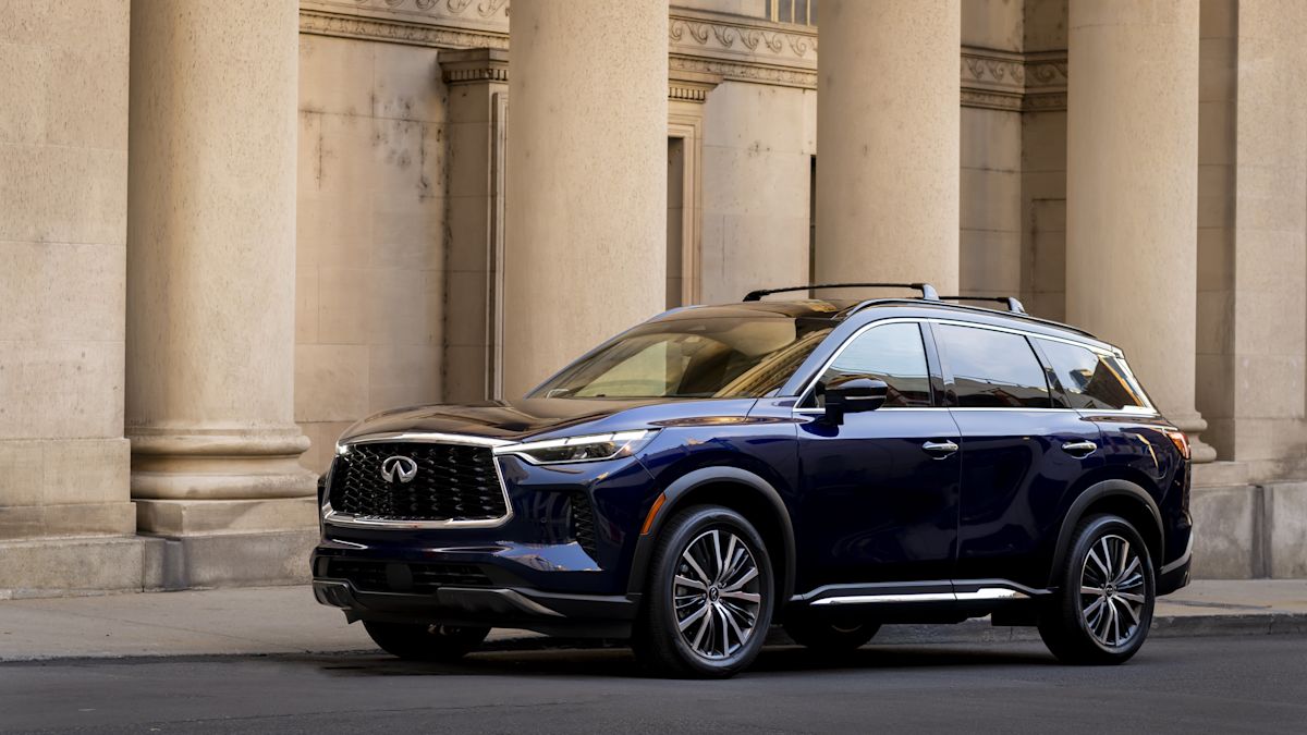 A navy QX60 is parked outside an impressive building with stone columns. 