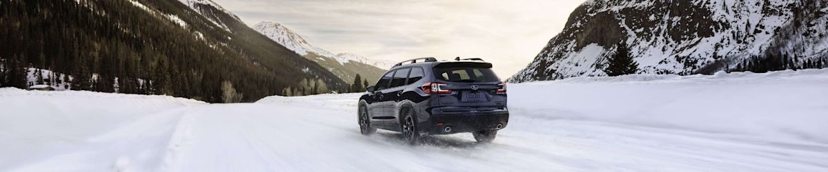 A blue Subaru Ascent easily navigates a snowy mountain road