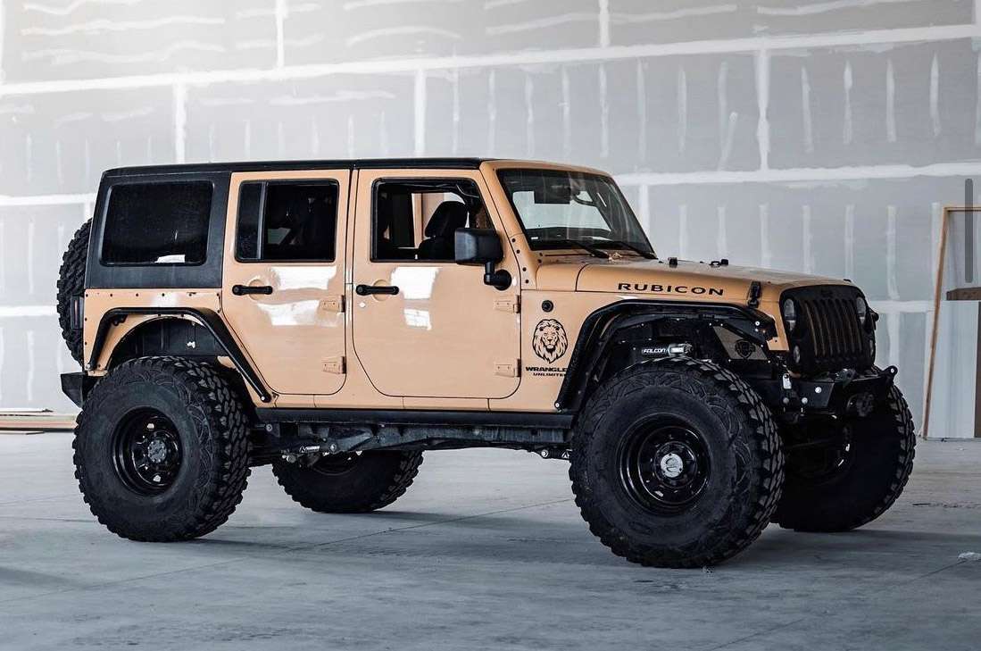 A profile of a tan colored jeep lays static on a granite surface.