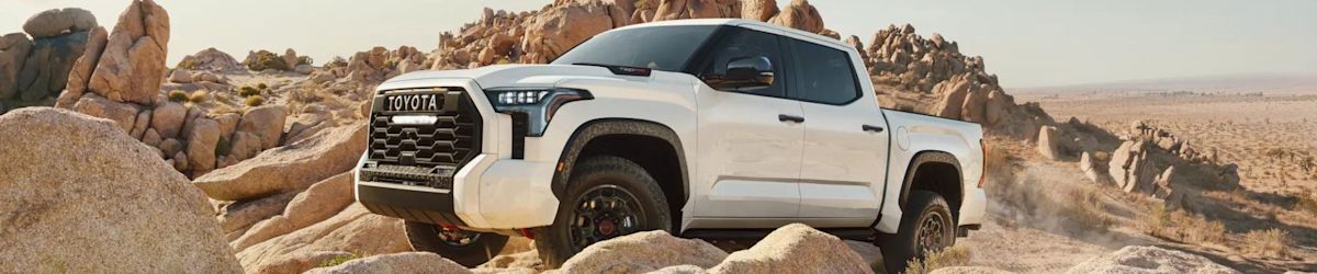 A white Toyota Tundra with a black grille crawls over rocky terrain with ease.