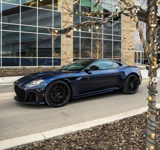 A black Aston Martin sits on a driveway.