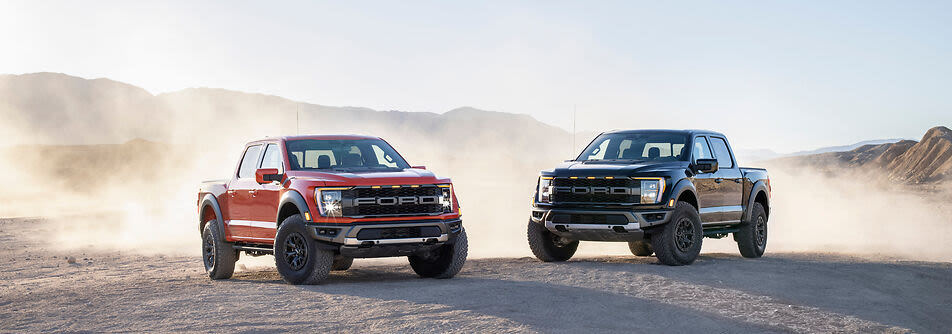 a red ford raptor and a black ford raptor next to each other