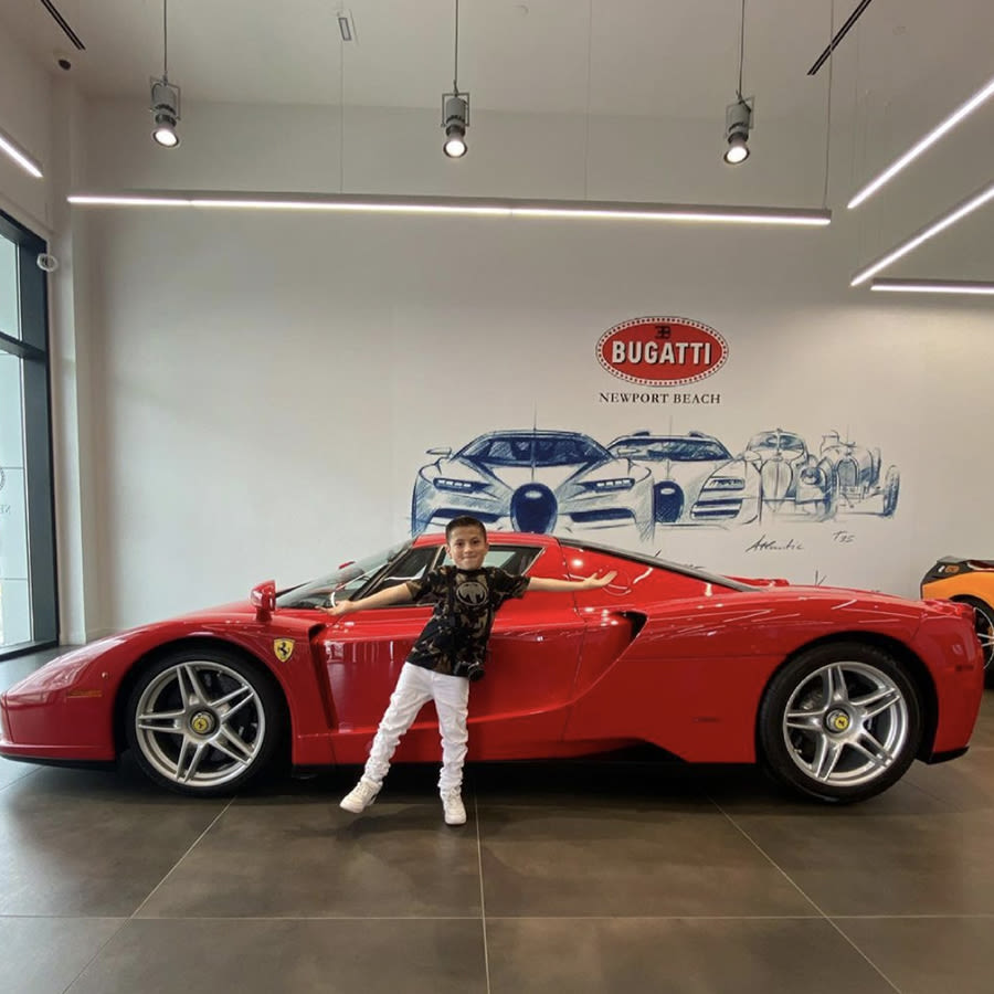 Sebastian Perez standing in front of a red ferrari at a Supercar dealership.