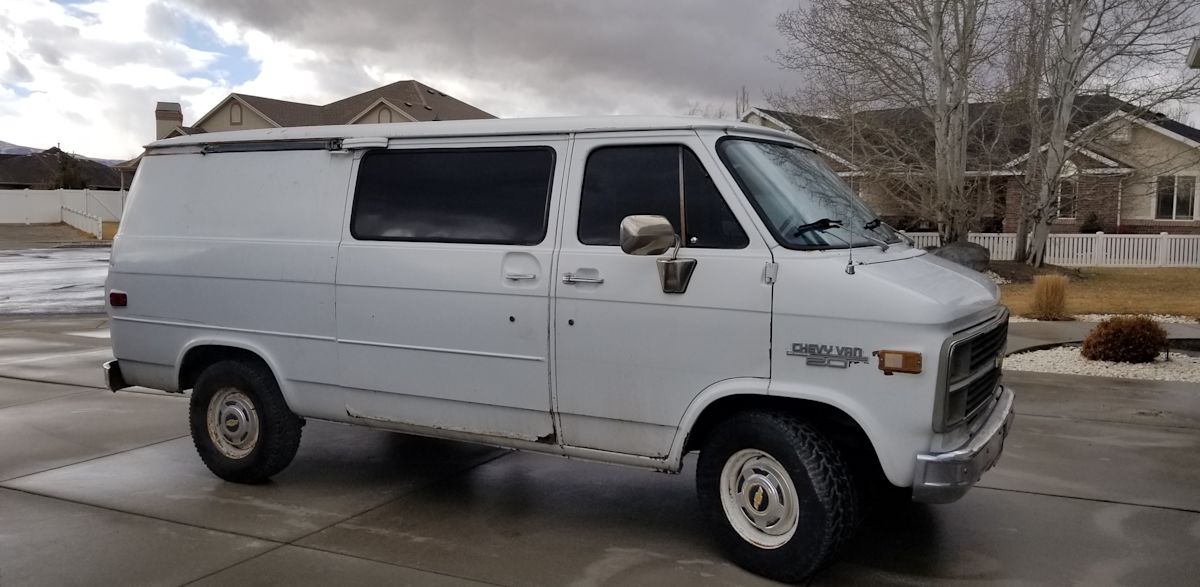 Side view of an old white van parked in a driveway