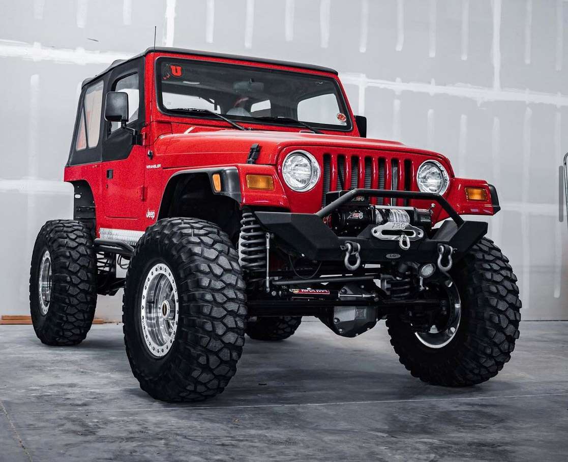 A bright red jeep sits static on a granite surface. 