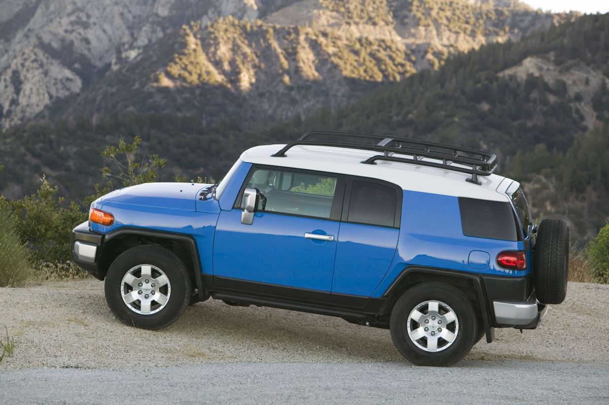 A blue FJ Cruiser sits parked beside a mountain road