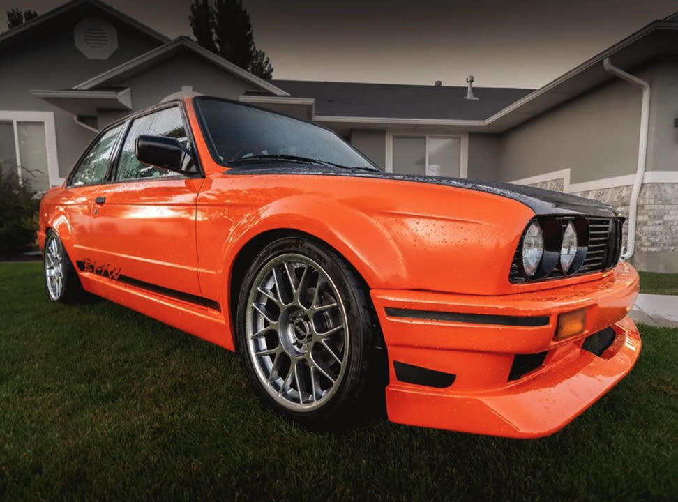 An orange BMW parked on green grass