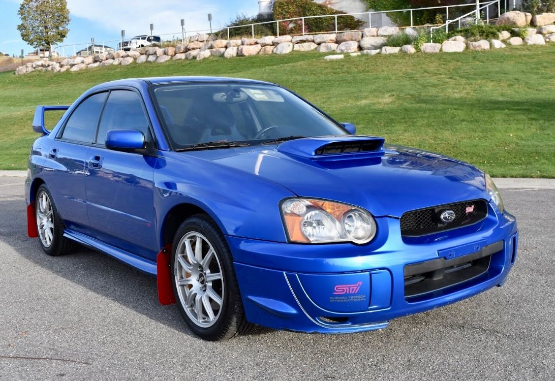 A blue Subaru WRX is parked on a road.