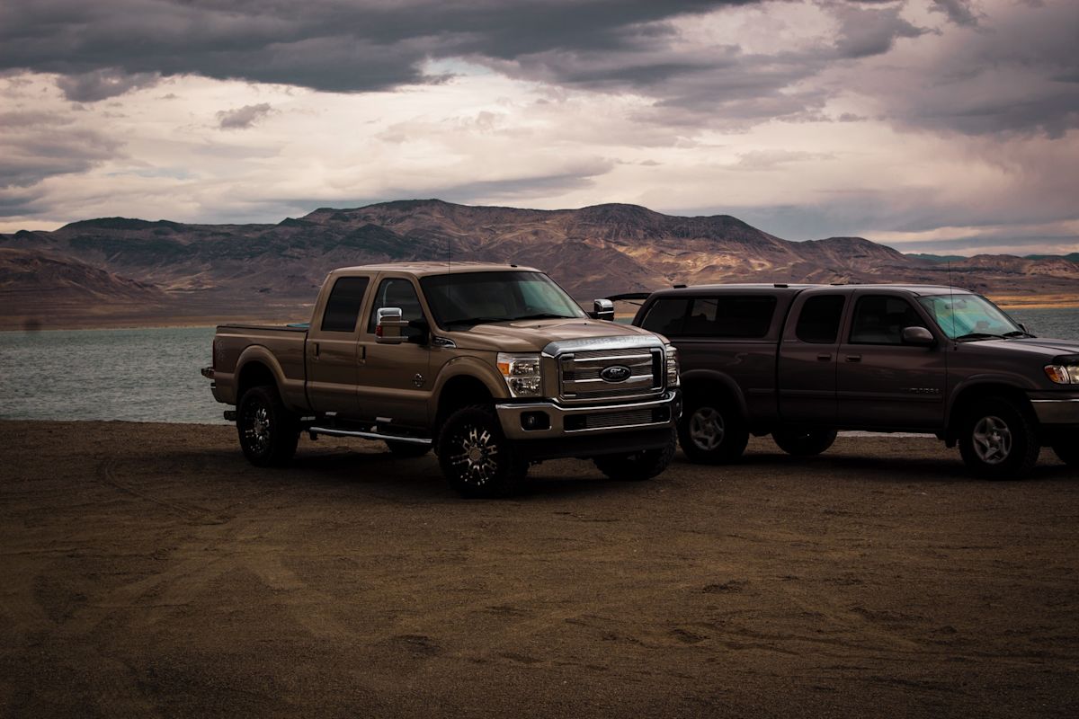 two trucks sitting side by side near a mountainous terrain