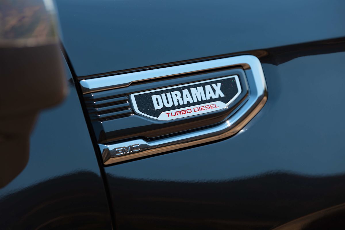 A closeup of a "Duramax Turbo Diesel" nameplate on a black truck. 